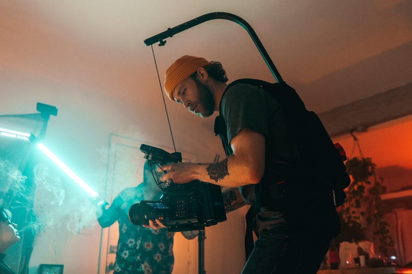 Man in Black T-shirt and Black Pants Holding Black Video Camera on Set